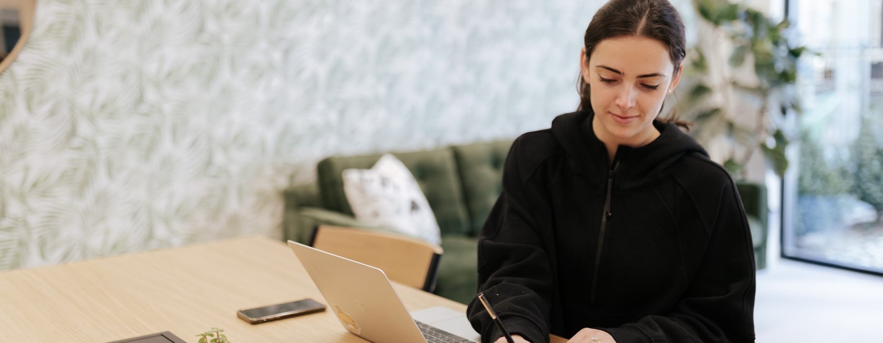 A resident sitting at a desk with a computer at Joinery Apartments in Charlotte, NC, featuring natural lighting.